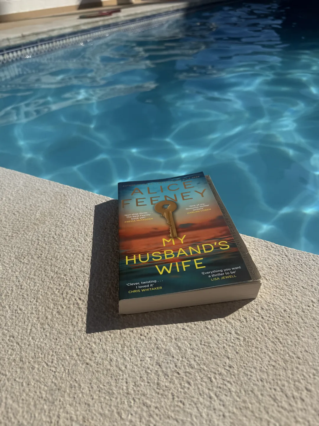 My Husband's Wife paperback beside the pool